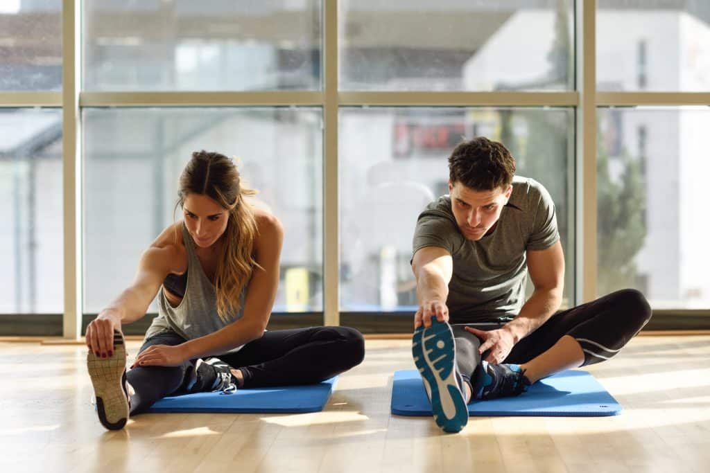 Deux personnes s'étirent sur des tapis de yoga.
