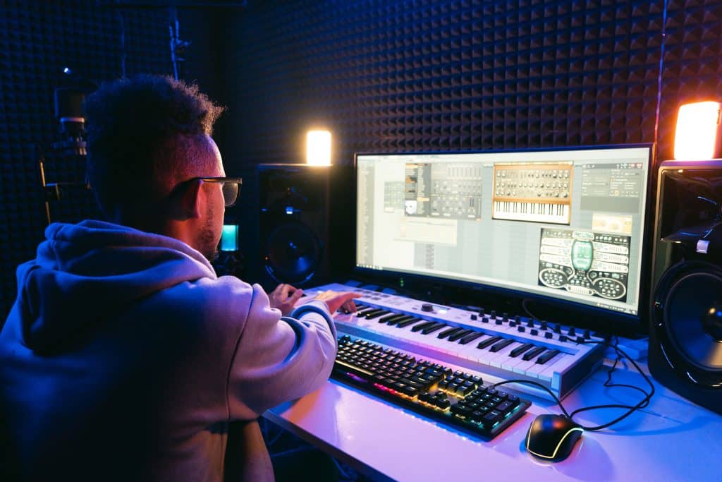 Musicien produisant sur ordinateur dans un studio insonorisé.