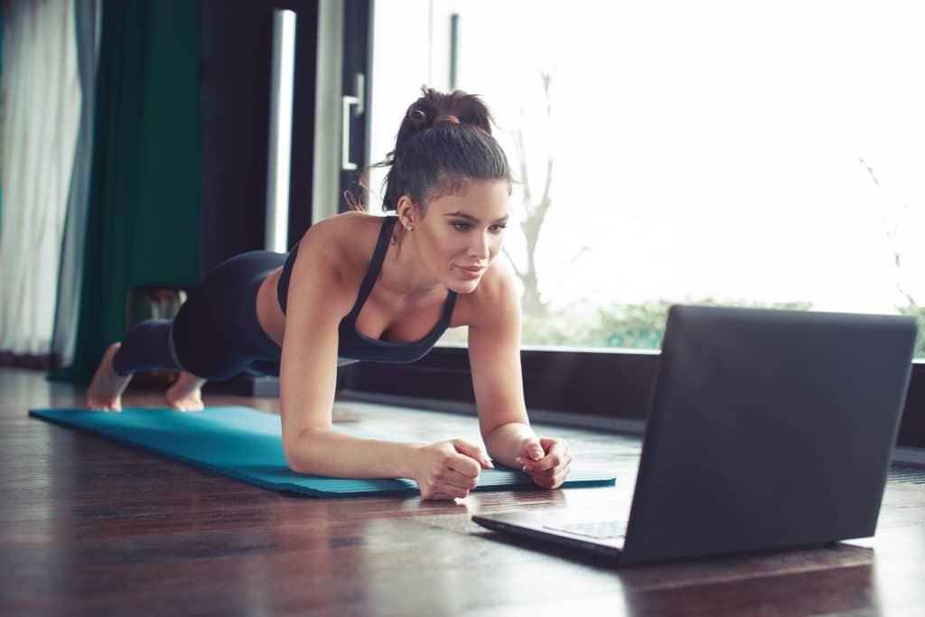 Femme faisant du sport devant un ordinateur portable.