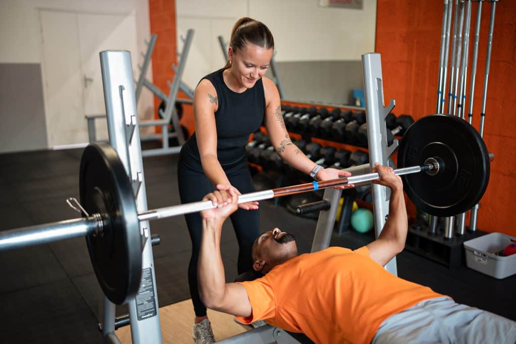 Coach sportive assistant un homme au développé couché