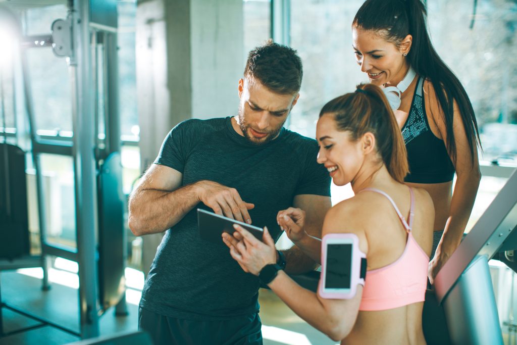 Trois sportifs regardant une tablette à la salle