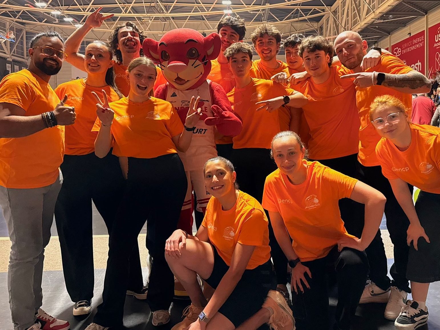 Équipe en t-shirts orange avec mascotte rouge