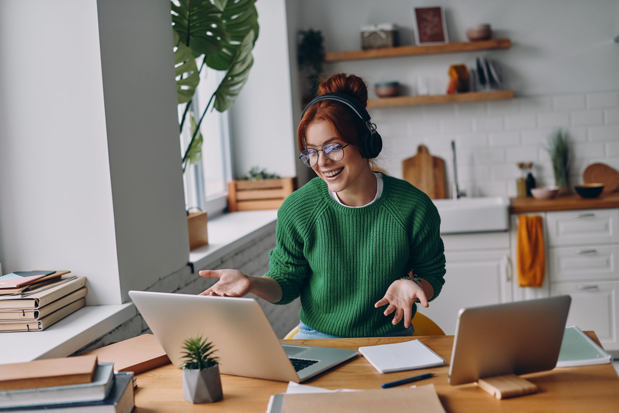 cheerful young woman in headphones having web conference while working from home Femme souriante en visioconférence avec casque et ordinateur
