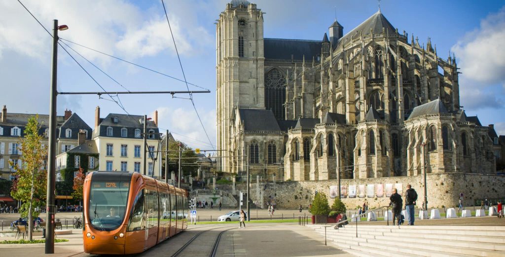 Tramway orange devant cathédrale gothique historique